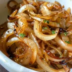 ['Close-up view of golden-brown caramelized onions in a pan.', 'Side angle of rich, glossy caramelized onions sizzling in olive oil.', 'Juicy caramelized onions with a glistening finish, showcasing their texture.', 'Warm, caramelized onion highlights with a soft, inviting appearance.']