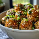 ['Close-up shot of juicy honey garlic chicken meatballs garnished with green onions and a glossy sauce.', 'Side view of succulent chicken meatballs coated in a rich honey garlic glaze, served on a white plate.', 'Detailed view of honey garlic chicken meatballs, showcasing their tender texture and vibrant color.', 'Appetizing close-up of chicken meatballs drizzled with honey garlic sauce, with fresh herbs sprinkled on top.']