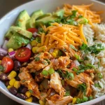 Close-up of a colorful Crock Pot Chicken Burrito Bowl with shredded chicken, rice, and toppings.
